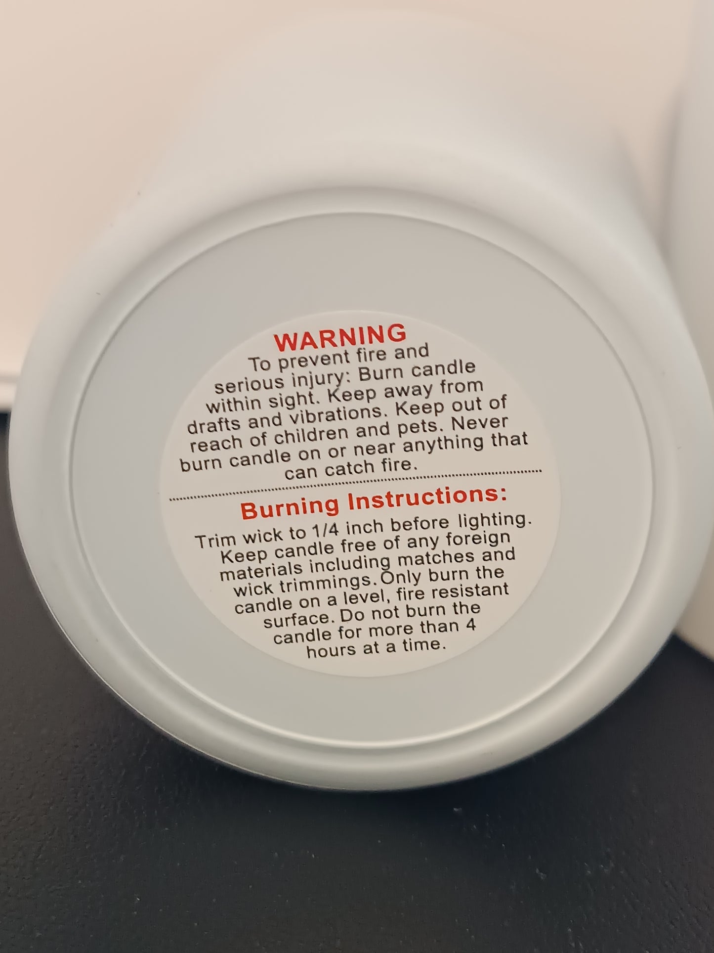 Warning and burn instructions affixed to the bottem of a white jar.