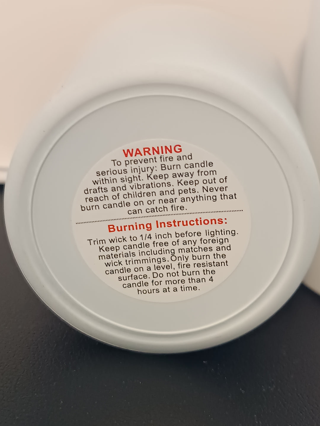 Warning and burn instructions affixed to the bottem of a white jar.