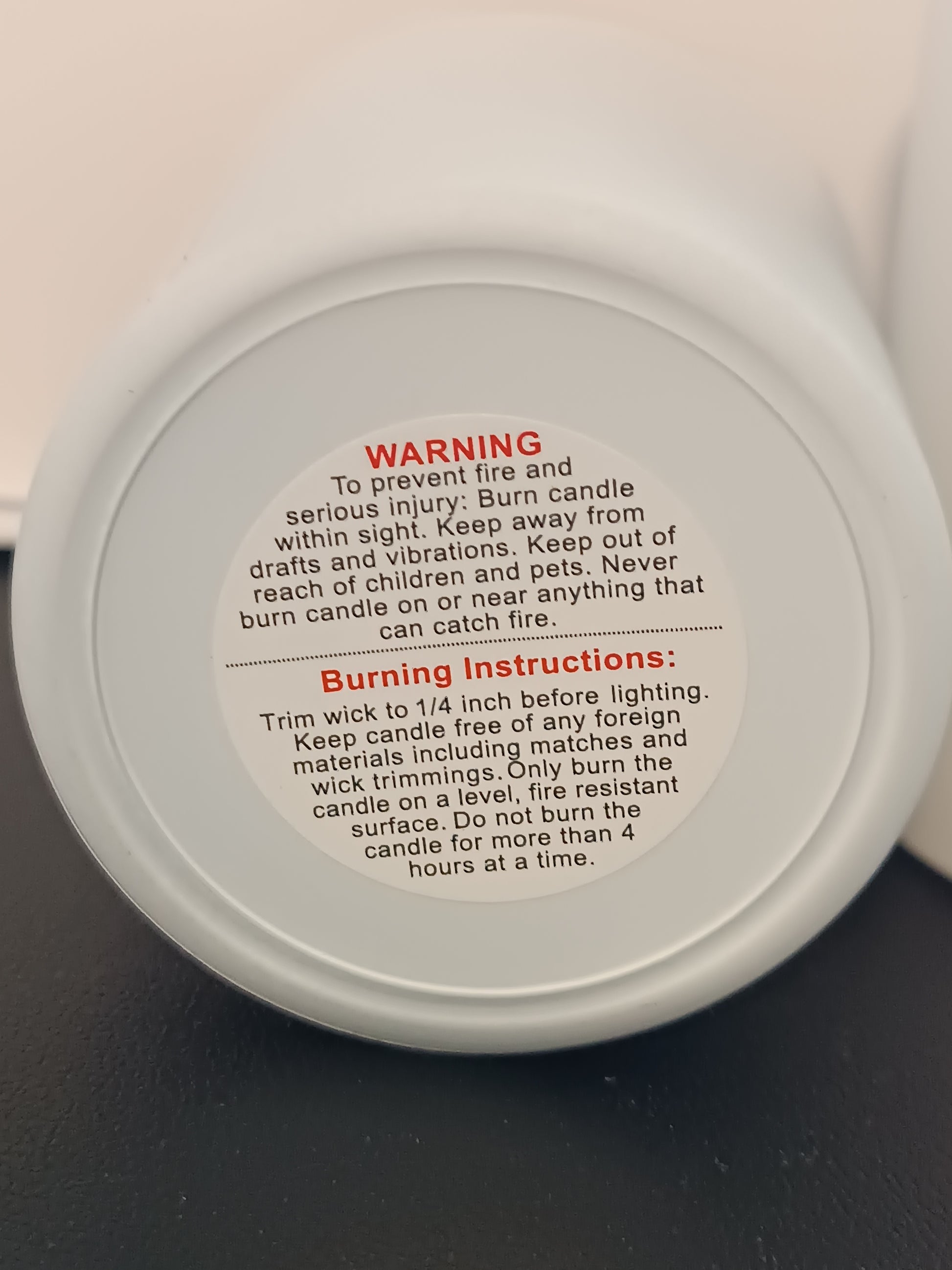 Warning and burn instructions affixed to the bottem of a white jar.