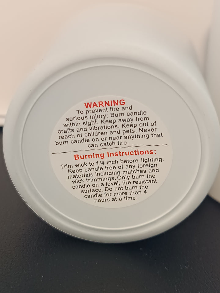 Warning and burn instructions affixed to the bottem of a white jar.