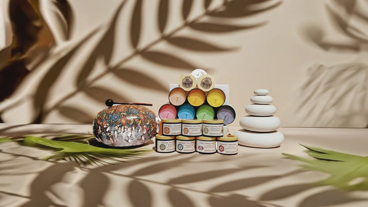 video of Chakra candle set by Luz del Mar Candles on a beige background with palm fran shadows gently waving over them.